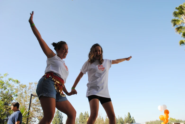 two girls are playing with a frisbee outside