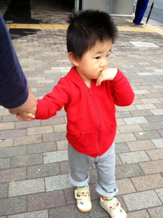 an image of little  walking with his hands on his mouth