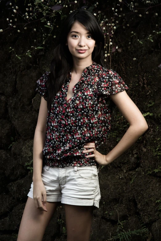 a woman stands against a wall wearing white denim shorts