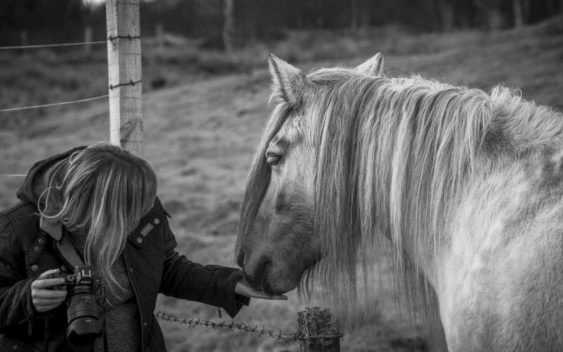 a black and white po of a woman petting a horse