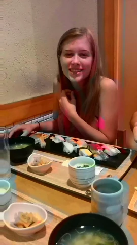 a girl sitting at the table in front of a sushi dish