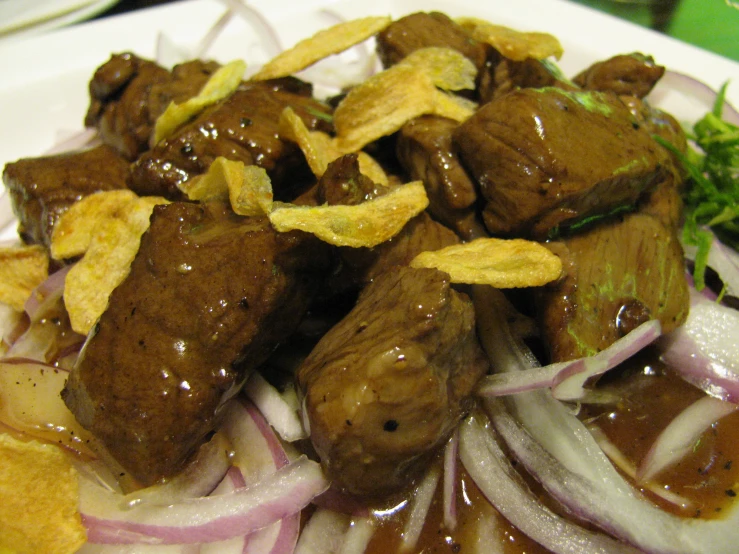 a plate of food with beef, onions, and chips