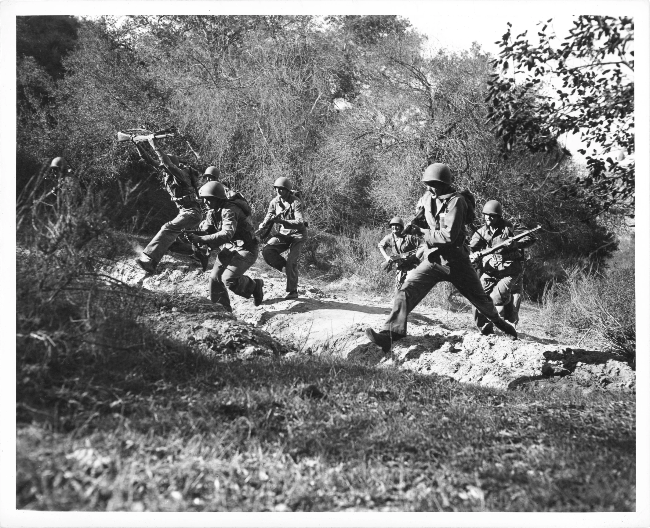 men are running through the woods in military uniforms