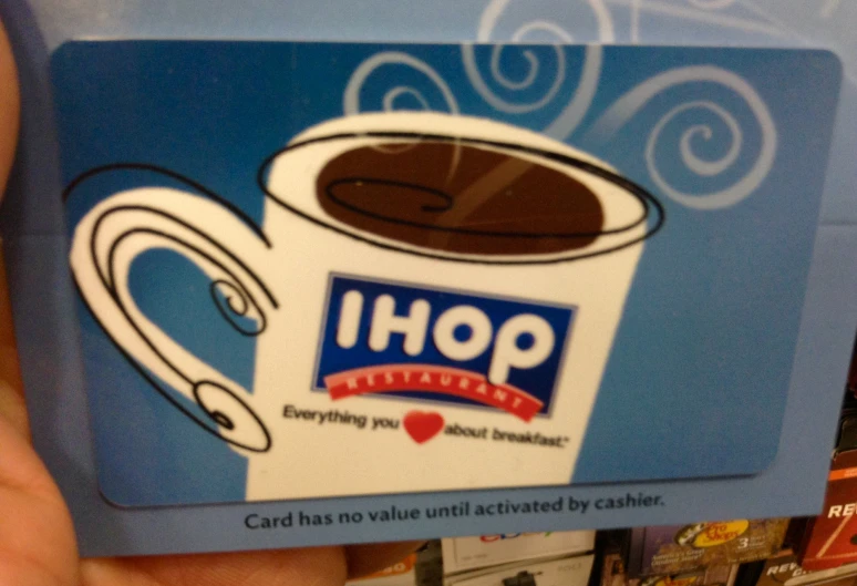 someone holding up an ihop card in front of a store shelf