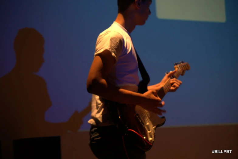 a person with a guitar is playing in front of a screen
