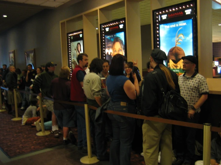 people standing in line with posters next to a row of seats