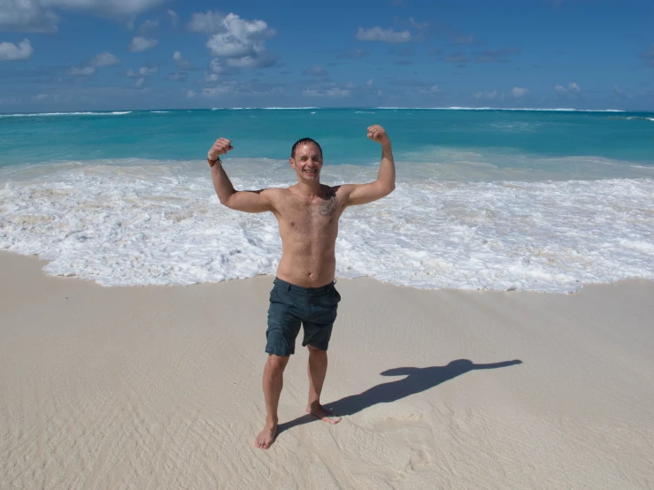 man standing on the beach flexing his muscles