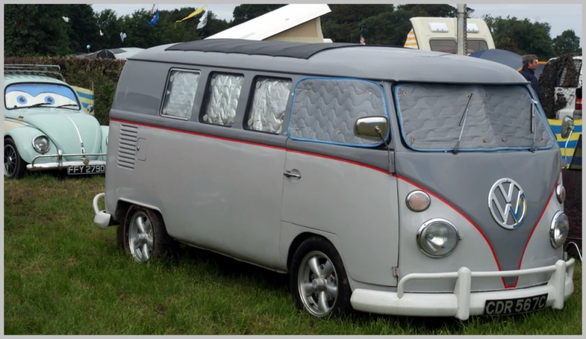 the van is parked on some grass and next to cars