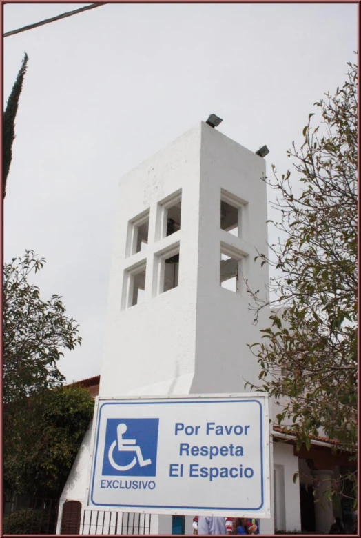 a white building with a man in a wheelchair sign in front of it