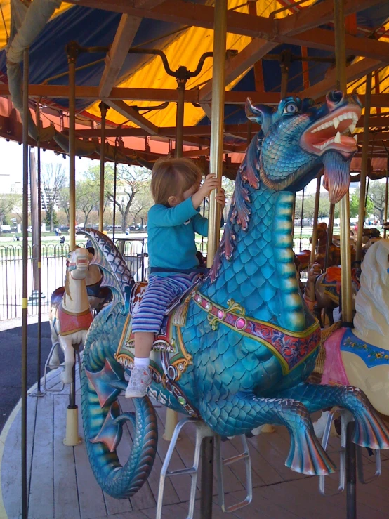 a young child rides on a carousel in a carnival