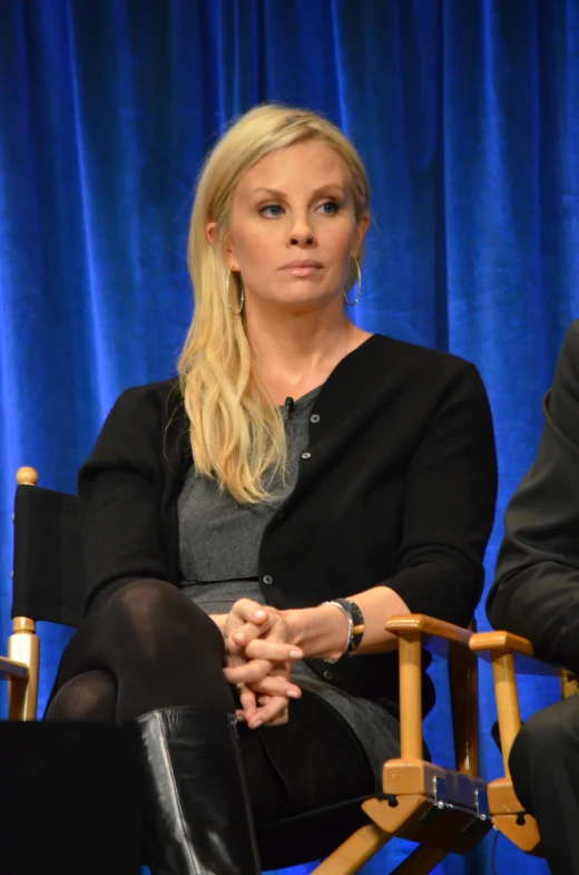 blonde woman in a black sweater sitting in a chair