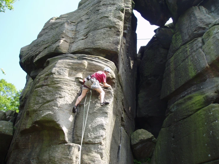 man climbing up the side of a tall rock formation