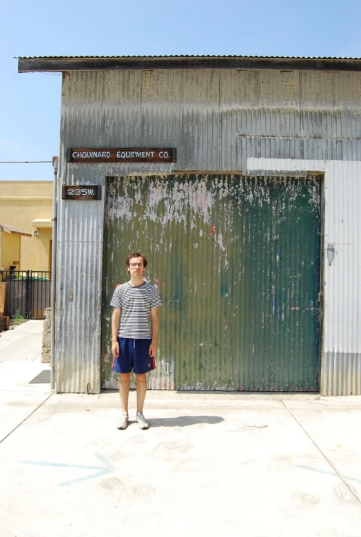 a man stands in front of a rusted metal building