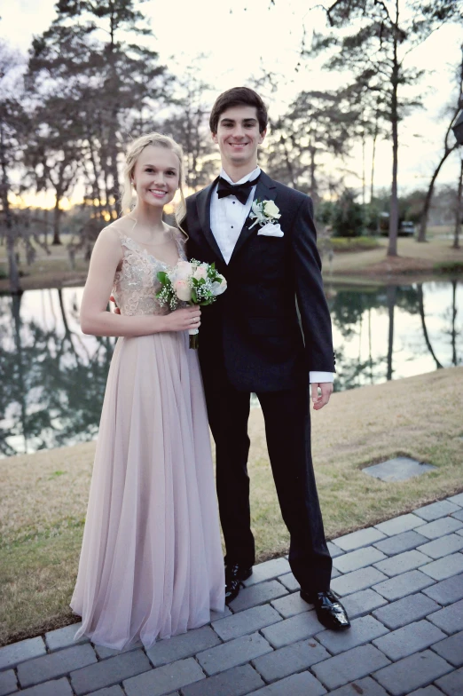 two people wearing formal wear next to a pond