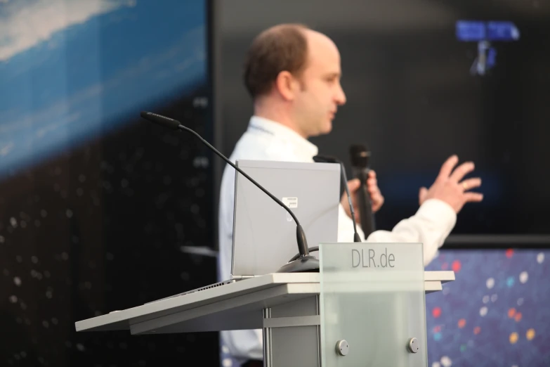 a man speaking on a stage while holding a microphone