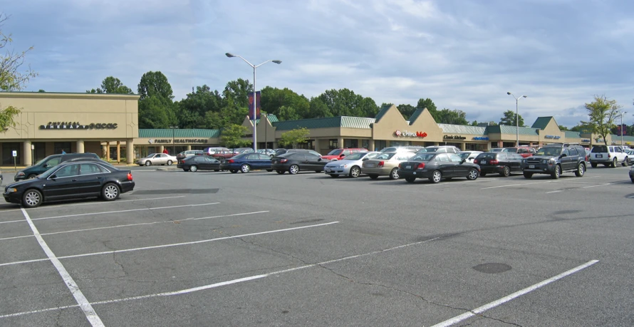 a parking lot full of parked cars next to shops