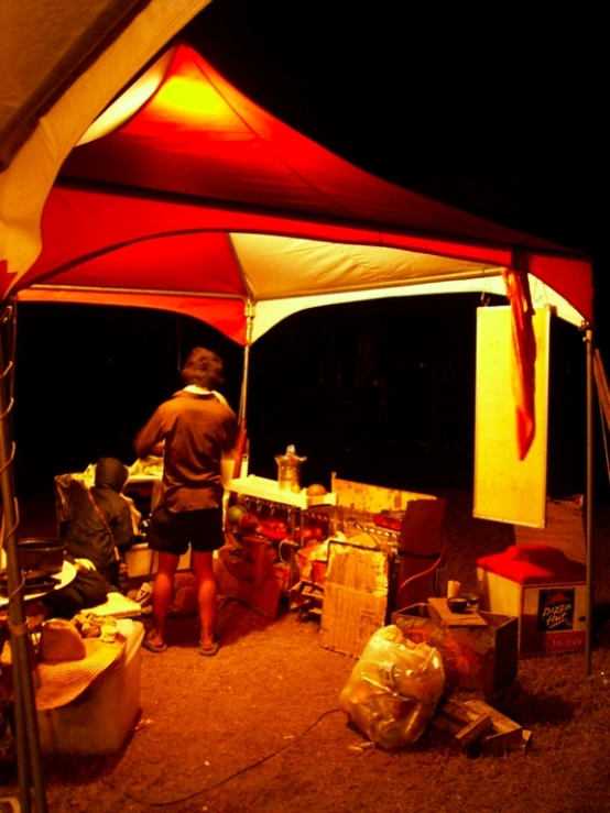 a man standing underneath a tent at night