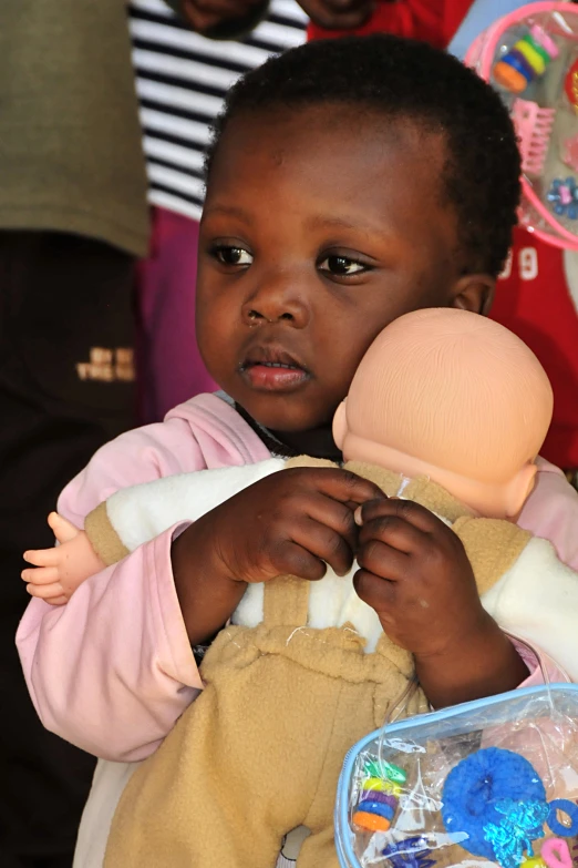 a child holding a doll and wearing a toy set