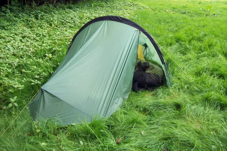 the man is laying down by the tent in the grass