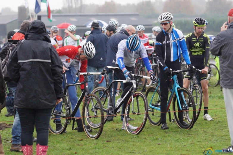 many bicycle riders are gathered on some grass