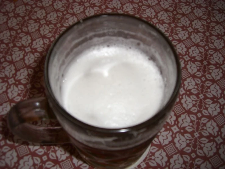 a glass mug full of milk on a table