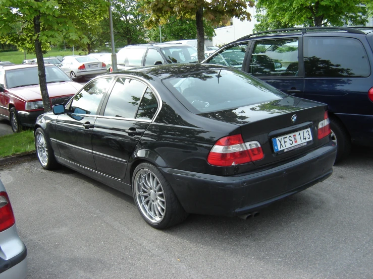 a black bmw parked next to other cars