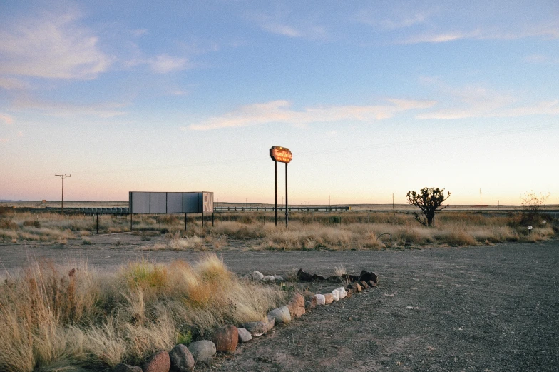 a dry field with some desert grass and a sky in the background