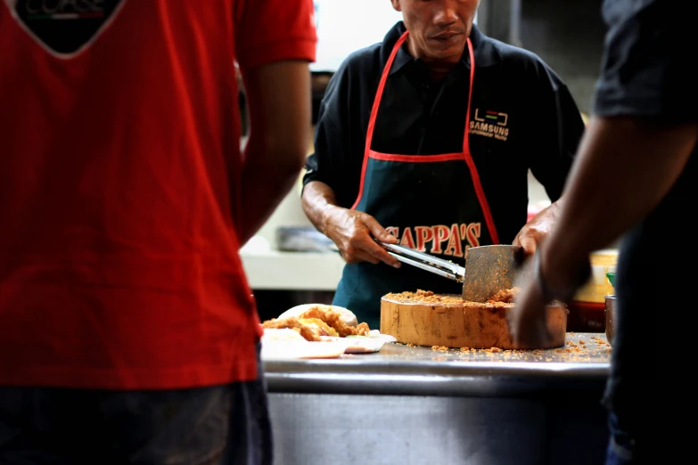 people working in an industrial kitchen slicing through the cake