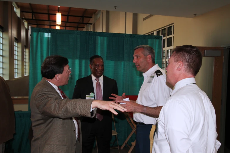 a man in a suit and tie shaking hands with three other men