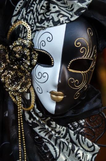 a mask with a face adorned by a fancy chain