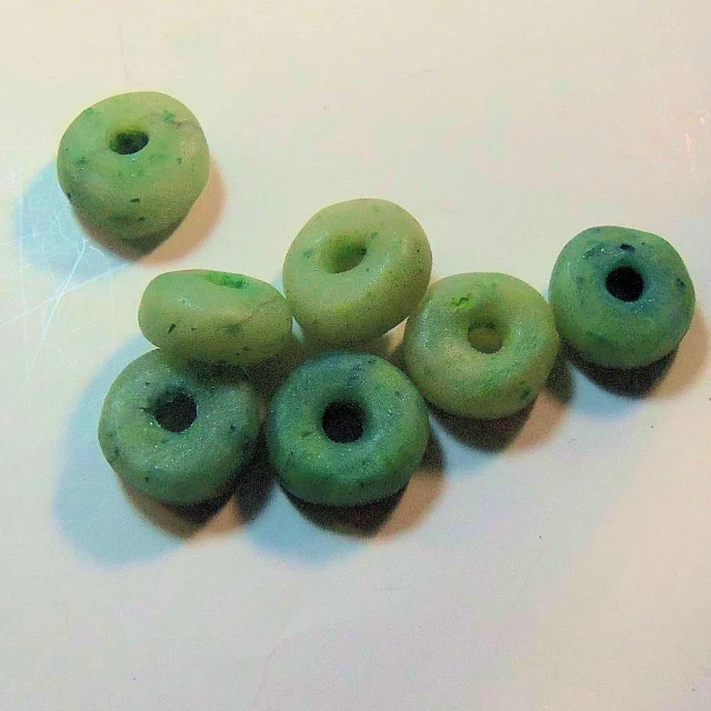 six green donuts sitting on top of a white counter