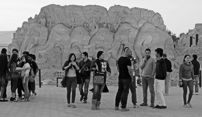 a group of people walking and talking next to some carved rocks