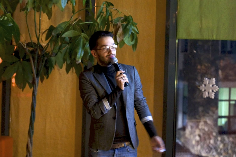 a man wearing glasses while talking into a microphone