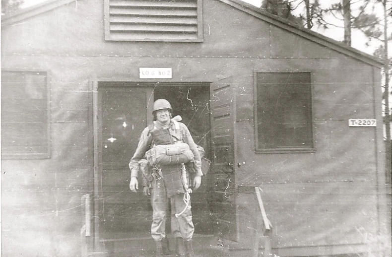 a man in army uniform holding an animal standing at a doorway