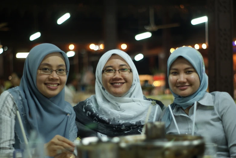 three women with heads covering sit next to each other