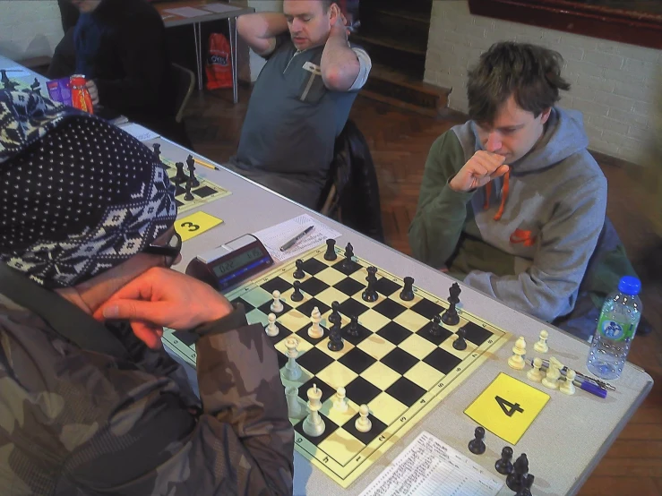 three people at a table playing chess together