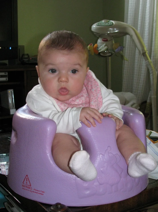 the baby is in a toy vehicle seat on the table