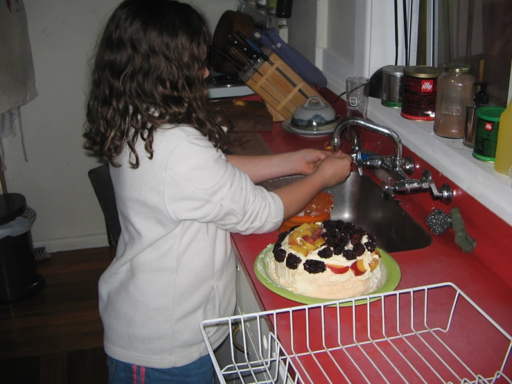 a woman placing blackberries on the top of a cake