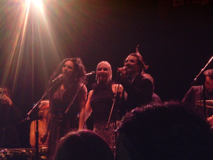 people singing and playing on stage with a group of musicians