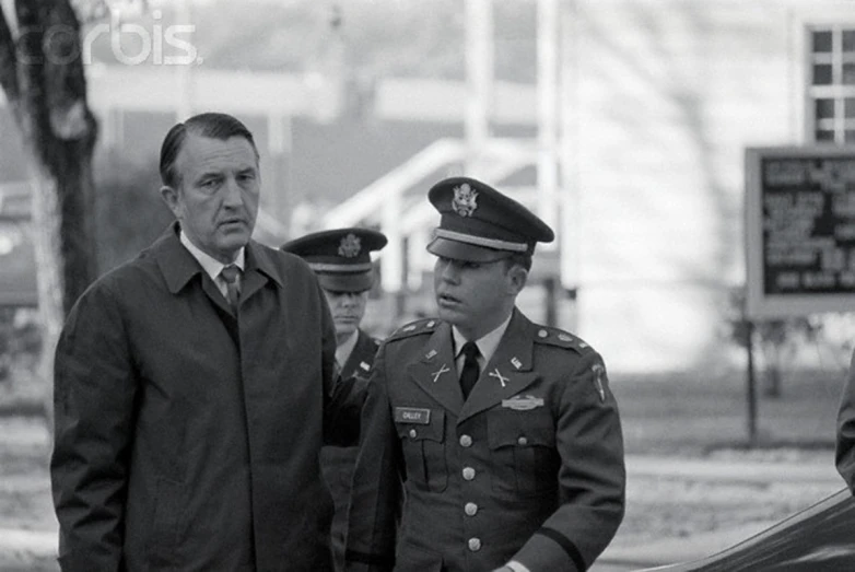 three soldiers talking to each other while two men talk in the background