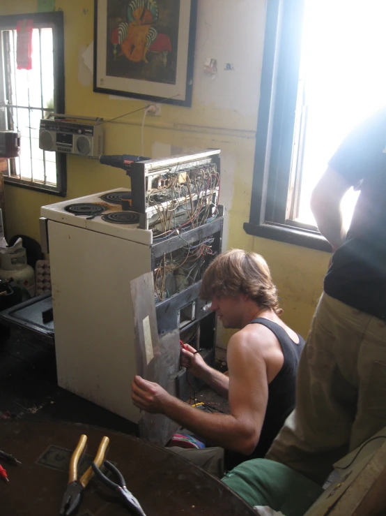 a young man in a workshop works on an electrical device