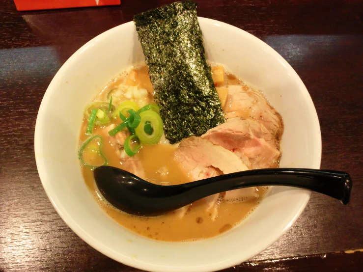 a white bowl on a table holds different types of food