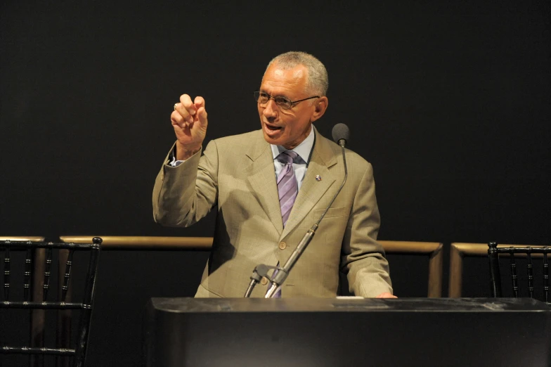 an older man wearing a suit gives a speech