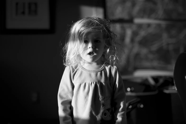 a little girl in black and white is standing by a wall