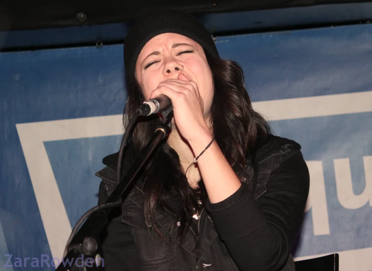 the woman is singing into a microphone with her hands