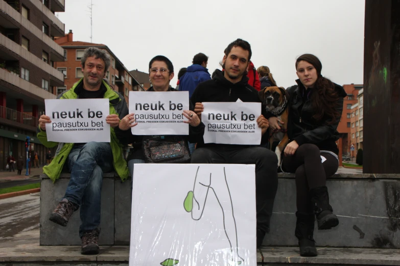 people sitting down holding signs while holding up various pictures