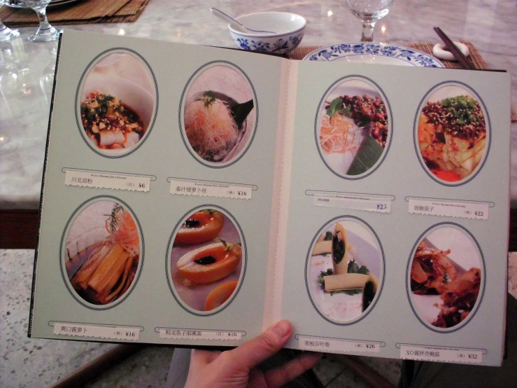 a person holding up a book with pictures and food
