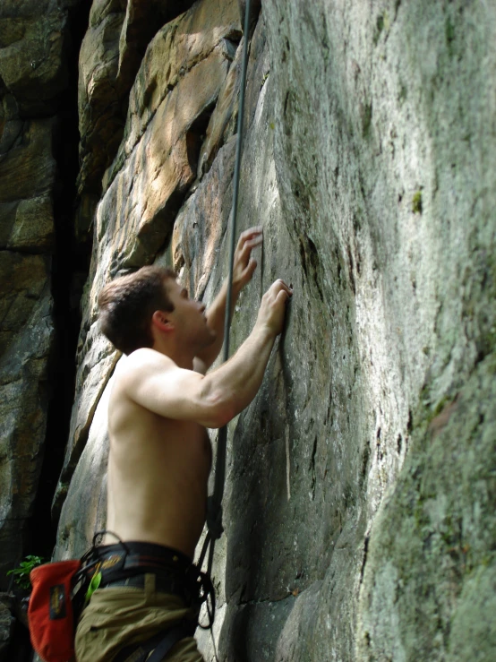 a shirtless male climber is holding his hand up to the face