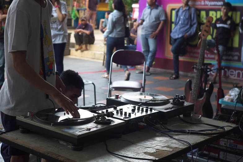 a man standing over a table top next to a record player