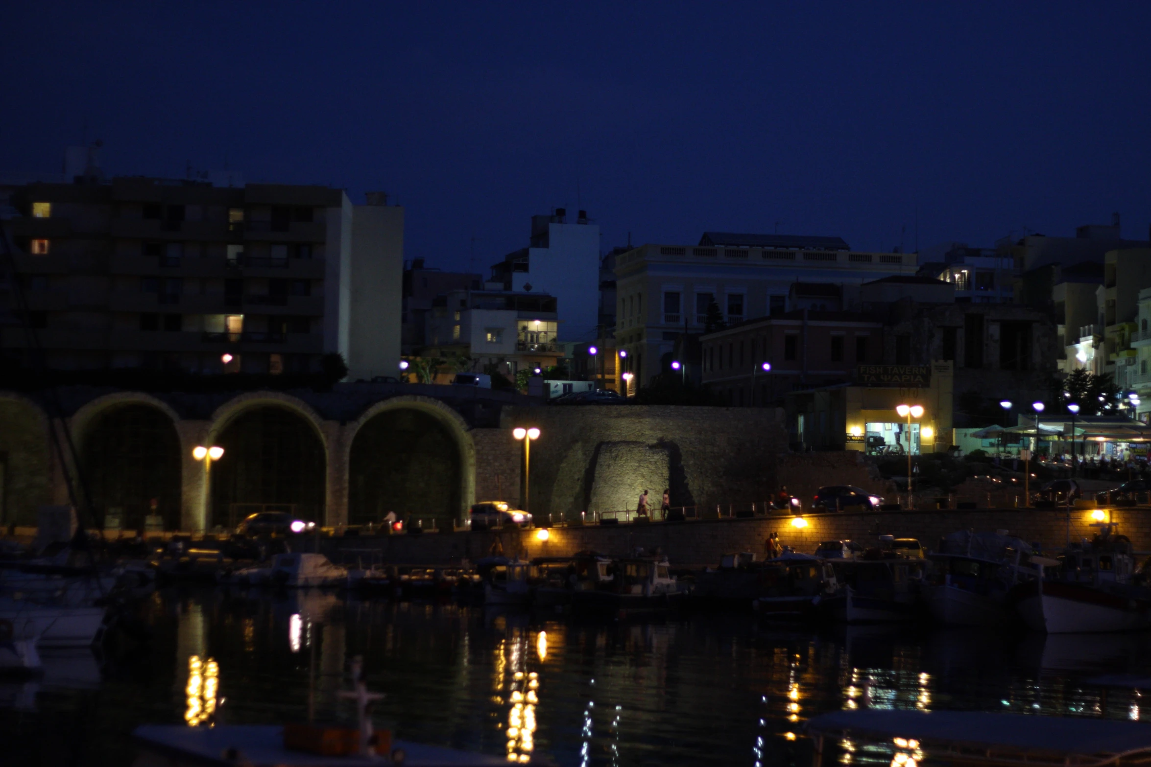 this is a night scene of a dock with lights reflecting off the water